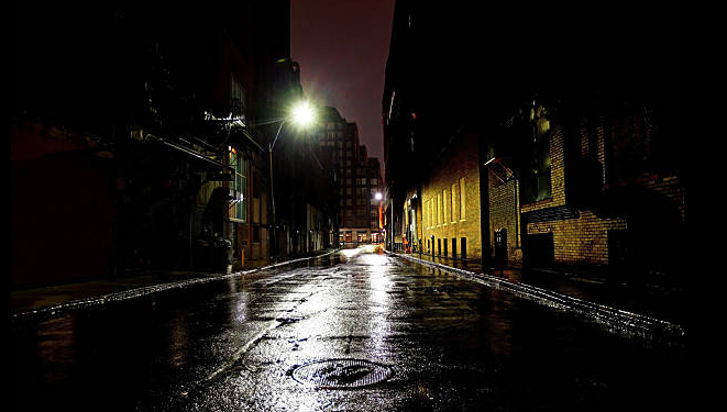 Wet city street at night lit by a single streetlight